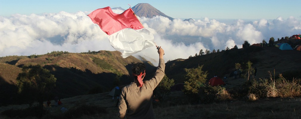 Man waving the Indonesian flag in the mountains